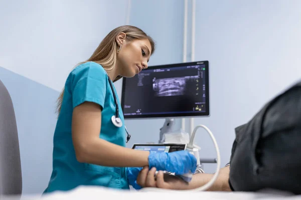 女医生在她的办公室里对病人的胳膊静脉进行超声波检查 在诊所通过超声波扫描的年轻人 医生的工作 医疗研究 — 图库照片