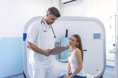 Kadın hasta, modern hastanedeki muayene prosedüründen sonra tomografiyle ilgili sorular soruyor.