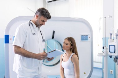 Bir teşhis tesisinde kadın hastaya MRI tarama prosedürünü açıklayan bir erkek doktor. Hastanenin Radyografisi Kadın Hasta BT Tarayıcısı ile.