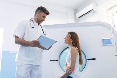 Kadın hasta, modern hastanedeki muayene prosedüründen sonra tomografiyle ilgili sorular soruyor.