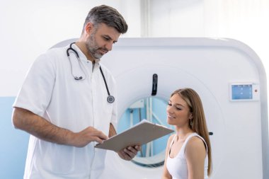 Kadın hasta, modern hastanedeki muayene prosedüründen sonra tomografiyle ilgili sorular soruyor.