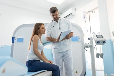 MRI taramasından önce erkek doktor kadına bilgi veriyor. Özel tıp kliniğinde manyetik rezonans görüntüleme teknolojisi.