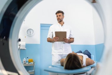 MRI taramasından önce erkek doktor kadına bilgi veriyor. Özel tıp kliniğinde manyetik rezonans görüntüleme teknolojisi.