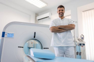 Modern bir hastanenin manyetik rezonans görüntüleme ya da bilgisayarlı tomografi odasında kendinden emin erkek doktor onkolojisi.