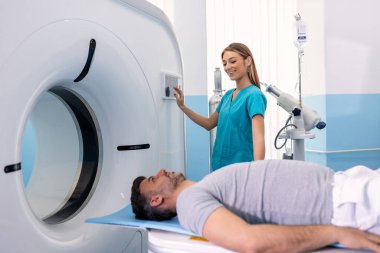 Tıbbi ekipman. Doktor ve hasta, hastanedeki bilgisayarlı tomografi odasında. 40 'lı yaşlarda genç bir kadın doktor tomografi cihazıyla adamı muayene ediyor. Bilgisayarlı tomografi.