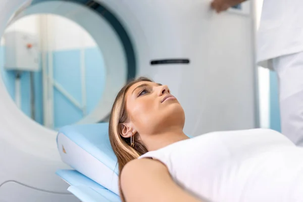 Female Patient Lying on a CT or PET or MRI Scan Bed, Moving Inside the Machine While it Scans Her Brain and Vital Parameters.