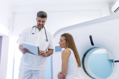 Ct tarayıcı yatakta oturup onun hasta konuşurken genç tıbbi teknisyen.