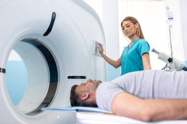 Female Doctor Looking At Patient Undergoing CT Scan. Doctor in uniform using tomography machine with lying patient in hospital clipart