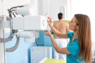 Hastanede, X-Ray Makinesi onu tararken, duvarın karşısında duran adam. Kırıklar, kırık uzuvlar, göğüs ve kanser taraması. Teknolojik Gelişmiş Tıbbi Ekipmanlı Modern Hastane.