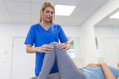 Fizyoterapide kıdemli bir hasta terapistiyle fiziksel egzersiz yapıyor. Yaşlı bir kadın için bacak fizyoterapisi yapıyor. Bacağındaki osteoartriti ve sinir ağrısını tedavi ediyor..