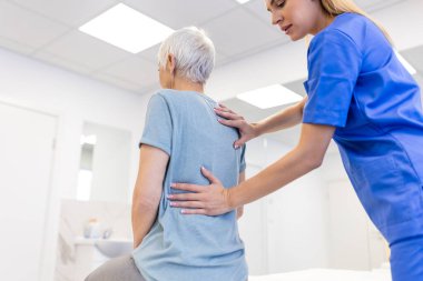 Kıdemli kadın kiropraktik sırt düzeltmesi yaptırıyor. Osteopati, alternatif tıp, ağrı kesici konsepti. Fizyoterapi, yaralanma rehabilitasyonu