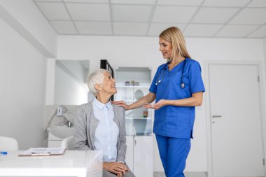 Beyaz üniformalı genç bir doktor ya da pratisyen hekim özel hastanedeki kadın hastaya danışıyor. Kadın terapist klinikte danışmanlık yapan üst düzey kadın müşteriyle konuşuyor..