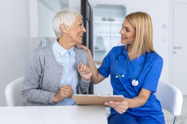 Beyaz üniformalı genç bir doktor ya da pratisyen hekim özel hastanedeki kadın hastaya danışıyor. Kadın terapist klinikte danışmanlık yapan üst düzey kadın müşteriyle konuşuyor..