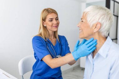 İlaç, sağlık ve sağlık muayenesi konsepti - hastanede hastanın bademciklerini kontrol eden doktor ya da hemşire. Endokrinolojist klinikteki yaşlı kadının boğazını inceliyor.