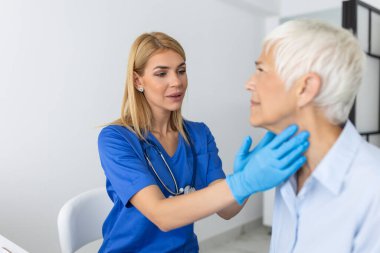 Klinikte kıdemli bir kadının boğazını inceliyor. Tiroid bezi testi olan kadınlar. Endokrinoloji, hormonlar ve tedavi. Boğaz iltihabı.