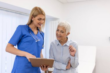 Mutlu genç bayan doktor terapisti modern klinik hastanesinde yaşlı kadın hastalara danışmanlık yapıyor. Tıbbi sağlık hizmeti kavramı.