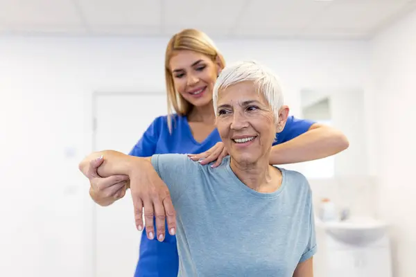 医生或理疗师检查老年女性患者受伤手臂的治疗 伸展运动 临床康复治疗疼痛 免版税图库照片