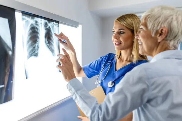 放射線と医学のコンセプト スクリーン上の肺スキャン結果を上級患者に説明する医師 ストックフォト