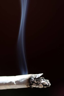 Siyah arka planda dumanla yanan sigaraya yakın çekim.