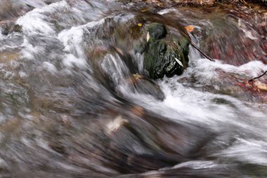Dar bir yolda akan güzel bir su akıntısının yakın görüntüsü.