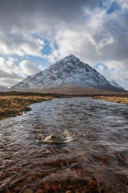 Önplanda Etive Nehri 'nin güzel kış manzarası. Arkaplanda ikonik kar örtülü Stob Dearg Buachaille Etive Mor dağı var.
