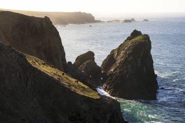 Corwnall İngiltere 'deki Kynance Koyu manzarası üzerinde göz kamaştırıcı bir gün doğumu canlı gökyüzü ve güzel turkuaz okyanusla