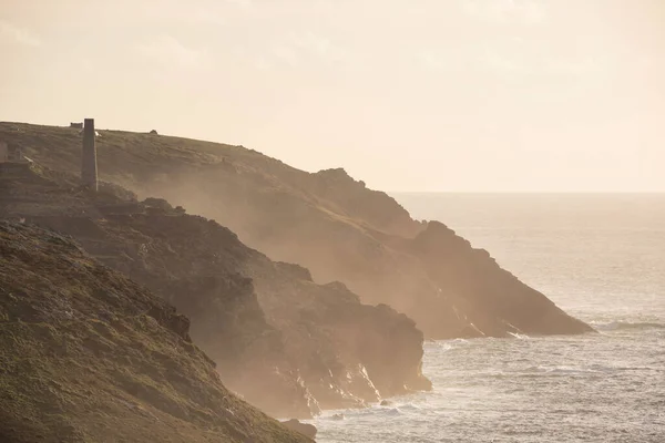 ペナディン灯台の岬から見た背景に錫鉱山とコーンウォールの崖の海岸線の美しい夕日の風景画像 — ストック写真