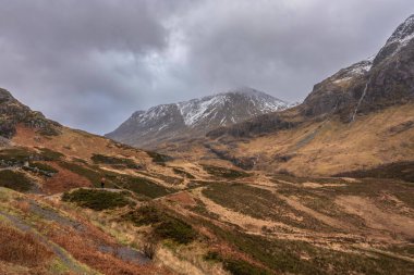 Glencoe İskoç dağlarında kar tepeli üç kız kardeşin dramatik gökyüzü eşliğinde destansı kış manzarası