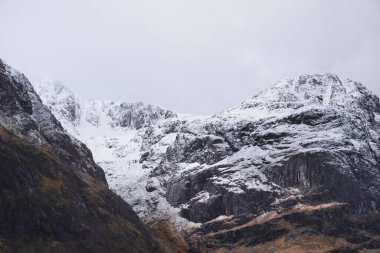 Glencoe İskoç dağlarında kar tepeli üç kız kardeşin dramatik gökyüzü eşliğinde destansı kış manzarası