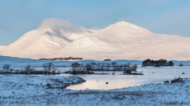 Beautiful landscape image in Winter looking across Lochan Na h-Achlaise towards mountain ranges in Scottish Highlands