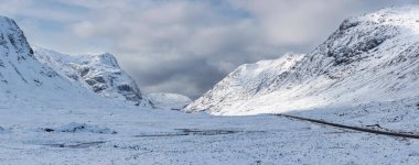 Güzel kış manzarası mavi gökyüzü görüntüsü Glencoe Rannoch Moor vadisi boyunca karla kaplı dağlar