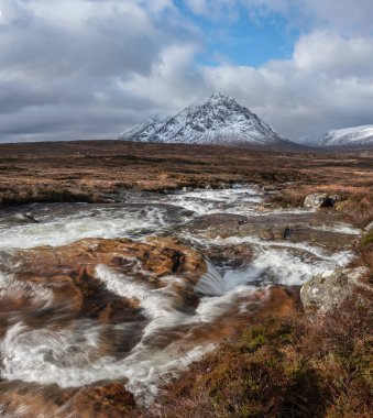 Önplanda Etive Nehri 'nin güzel kış manzarası. Arkaplanda ikonik kar örtülü Stob Dearg Buachaille Etive Mor dağı var.