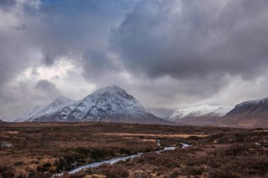 Stob Dearg Buachaille Etive Mor 'un kış manzarası. Rannoch Moor' dan karlı zirvesi ve güzel dramatik bulut oluşumlarıyla izleniyor.