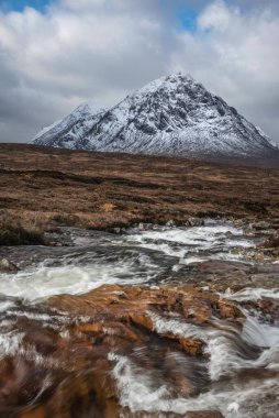Önplanda Etive Nehri 'nin güzel kış manzarası. Arkaplanda ikonik kar örtülü Stob Dearg Buachaille Etive Mor dağı var.