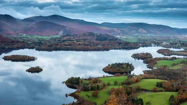 Epic landscape Autumn image of view from Walla Crag in Lake District, over Derwentwater looking towards Catbells and distant mountains with stunning Fall colors and light