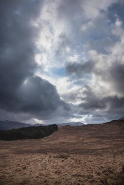 Büyük dramatik fırtınalı gökyüzü İskoçya 'daki karlı dağların üzerindeki manzara.