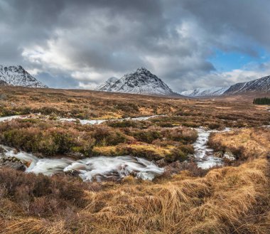 Önplanda Etive Nehri 'nin güzel kış manzarası. Arkaplanda ikonik kar örtülü Stob Dearg Buachaille Etive Mor dağı var.