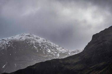Beautiful Winter landscape view along Loch Leven past Ballachulish Bridge towards snowcapped mountains in distance with dramatic sky