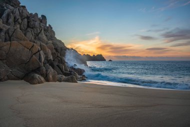 Cornwall İngiltere 'deki Porthcurno plajında büyüleyici renkler ve ruh haliyle güzel bir gün doğumu manzarası.
