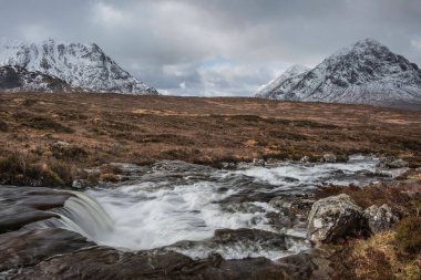 Önplanda Etive Nehri 'nin güzel kış manzarası. Arkaplanda ikonik kar örtülü Stob Dearg Buachaille Etive Mor dağı var.
