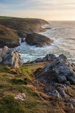Günbatımında Cornwall uçurumunun muhteşem manzarası. Pendeen Deniz Feneri Burnu 'ndan arka planda kalay madenleri görülüyor.