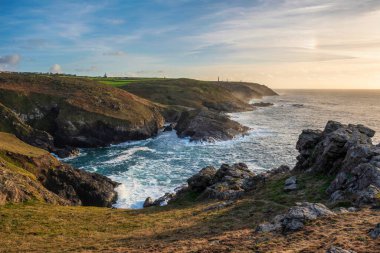 Günbatımında Cornwall uçurumunun muhteşem manzarası. Pendeen Deniz Feneri Burnu 'ndan arka planda kalay madenleri görülüyor.
