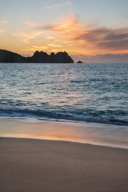 Cornwall İngiltere 'deki Porthcurno plajında büyüleyici renkler ve ruh haliyle güzel bir gün doğumu manzarası.