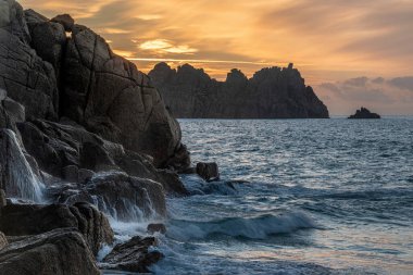 Cornwall İngiltere 'deki Porthcurno plajında büyüleyici renkler ve ruh haliyle güzel bir gün doğumu manzarası.