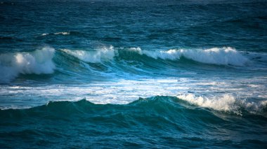 Cornwall 'daki Sennen Koyu' na güneş batarken çarpan güçlü büyük turkuaz renkli dalgalar.