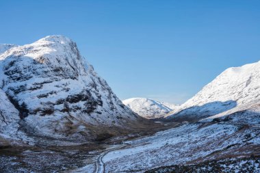 Güzel kış manzarası mavi gökyüzü Glencoe Rannoch Moor vadisi boyunca etrafı karla kaplı dağlarla