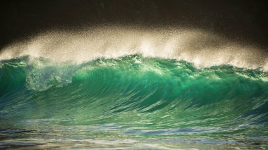 Yeşim turkuaz dalgaların kıyıya çarptığı destansı manzara görüntüsü ve Kynance Cove Cornwall 'daki kayalar, parlayan gündoğumu arka planı ve rüzgardaki su damlacıkları.