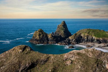 Cornwall İngiltere 'deki Kynance Koyu manzarası üzerinde göz kamaştırıcı bir gün doğumu canlı gökyüzü ve güzel turkuaz okyanusla