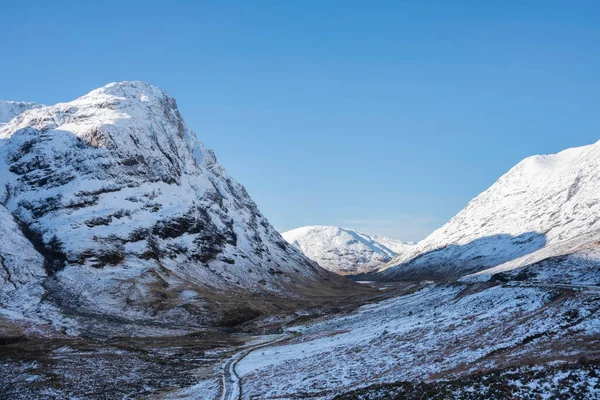 Güzel kış manzarası mavi gökyüzü Glencoe Rannoch Moor vadisi boyunca etrafı karla kaplı dağlarla