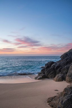 Cornwall İngiltere 'deki Porthcurno plajında büyüleyici renkler ve ruh haliyle güzel bir gün doğumu manzarası.